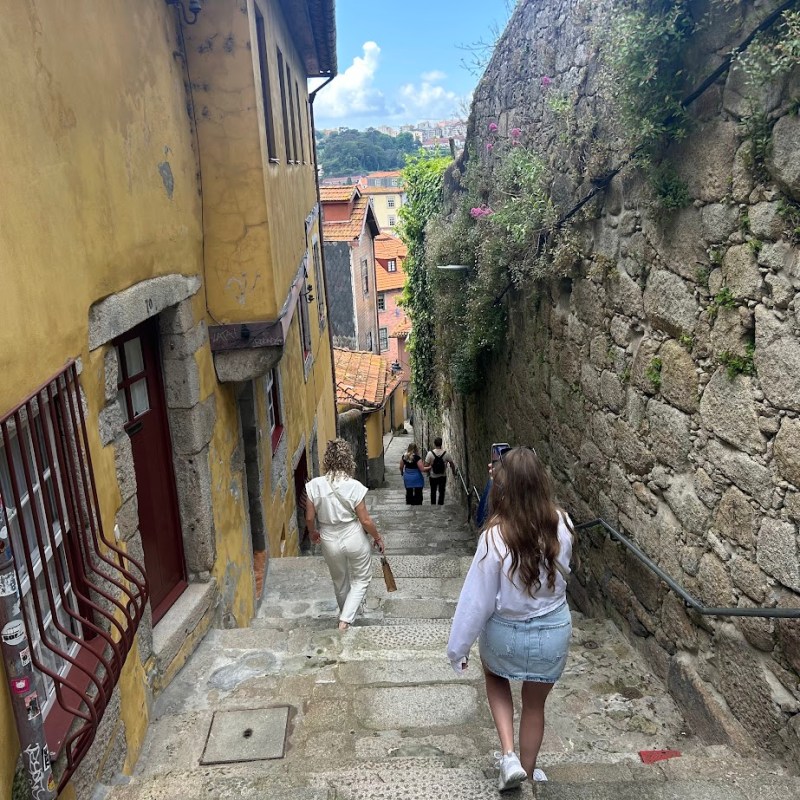 a little girl standing next to a stone wall