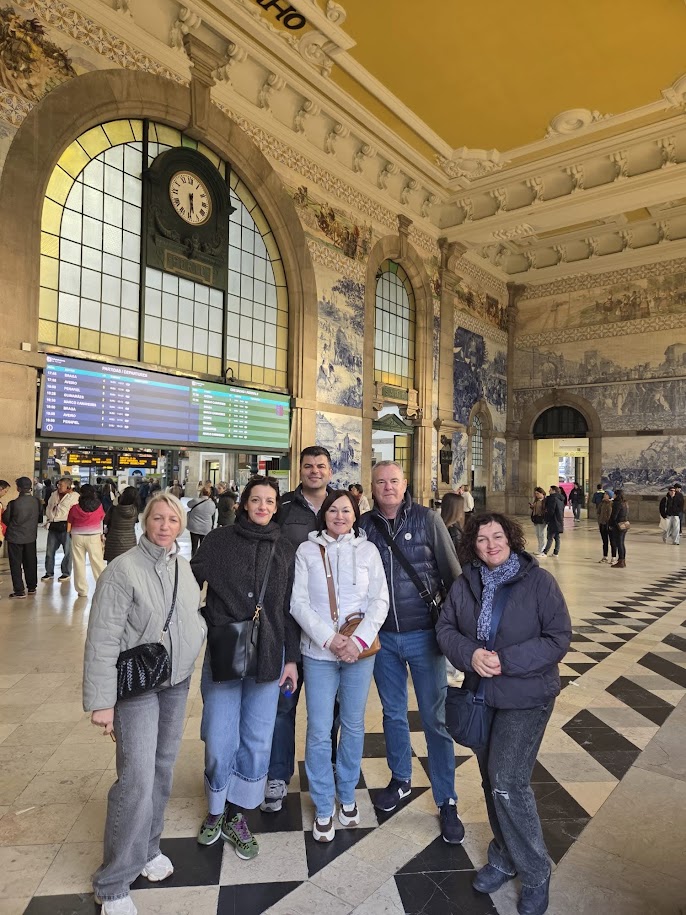 Group of people posing inside a large, ornate train station.